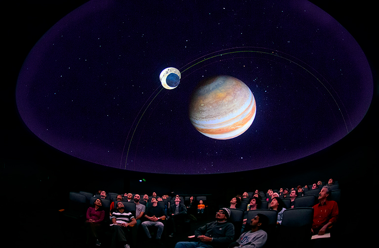 Audience watches a planetarium show.