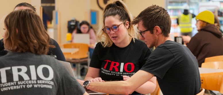 Group of people working together, all wearing TRIO shirts to represent the student support programs at UW.