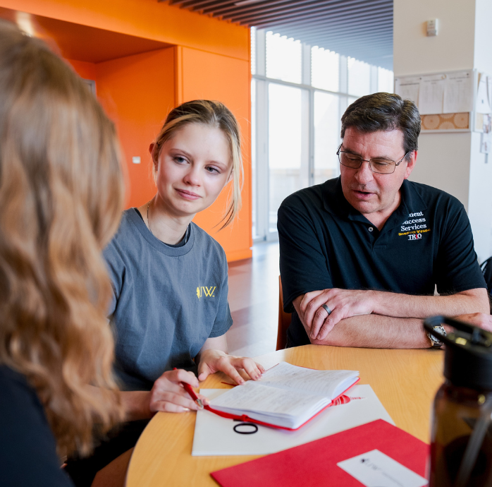 Image of three people working together. 