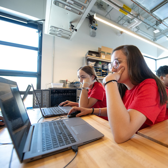 Two students working intently on laptops.