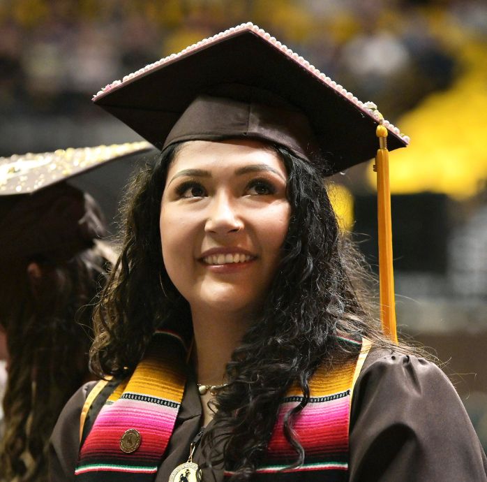 Image of a woman smiling in her commencement regalia.