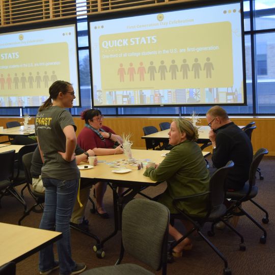 A group of people, including Jenna Krieschel and Kate McLaughlin both former first-generation students, watch a presentation at the 2023 National First-Generation College Student Celebration Day. 