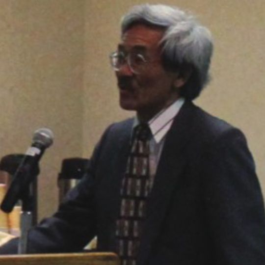 Aged photo of Dr. Fuji Adachi speaking at a podium.