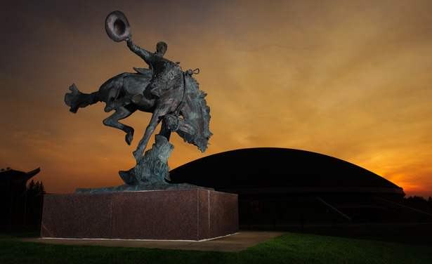 Image of a Steamboat statue on campus with sunset and Arena Auditorium behind.