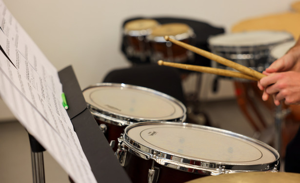 Focused image of a drum set with someone holding drum sticks.