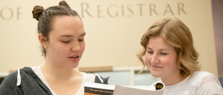 Student and advisor looking over a book together. 