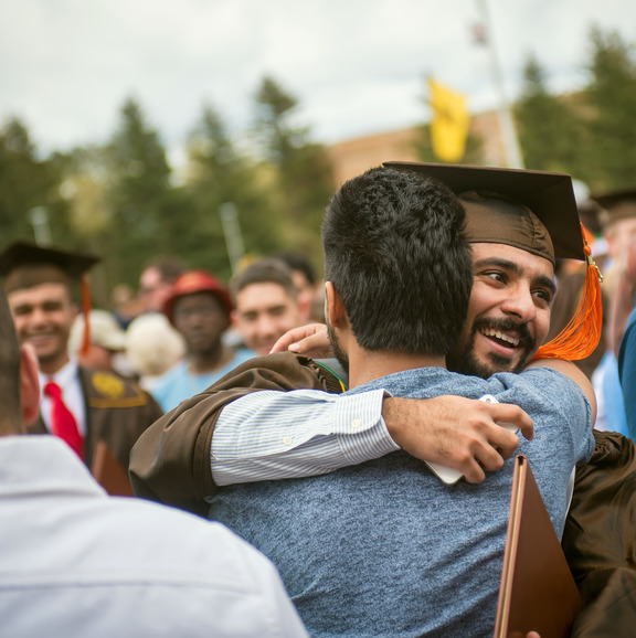 A student's graduation cap decorated with 'UW' and flowers carved into leather, during a commencement ceremony.