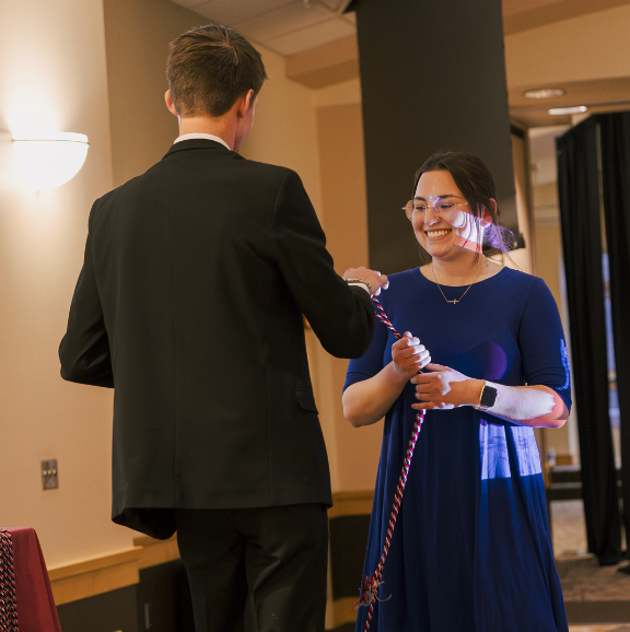 Image of a TRIO advisor handing a recent SSS graduate an honor cord at the annual Student Recognition Dinner.