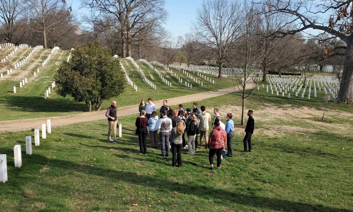 A group of students stand outside and listen to a tour guide