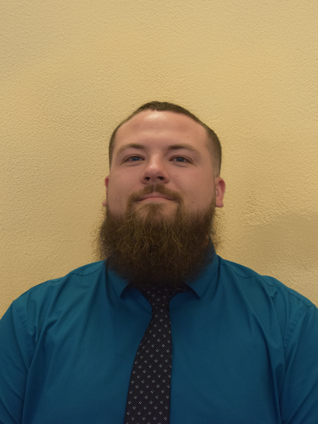 Devin LaGois stands in front of a beige wall.