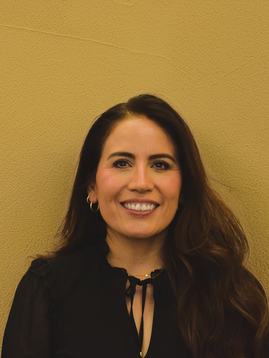 Luz Urquijo-Hawkes stands in front of a beige wall.