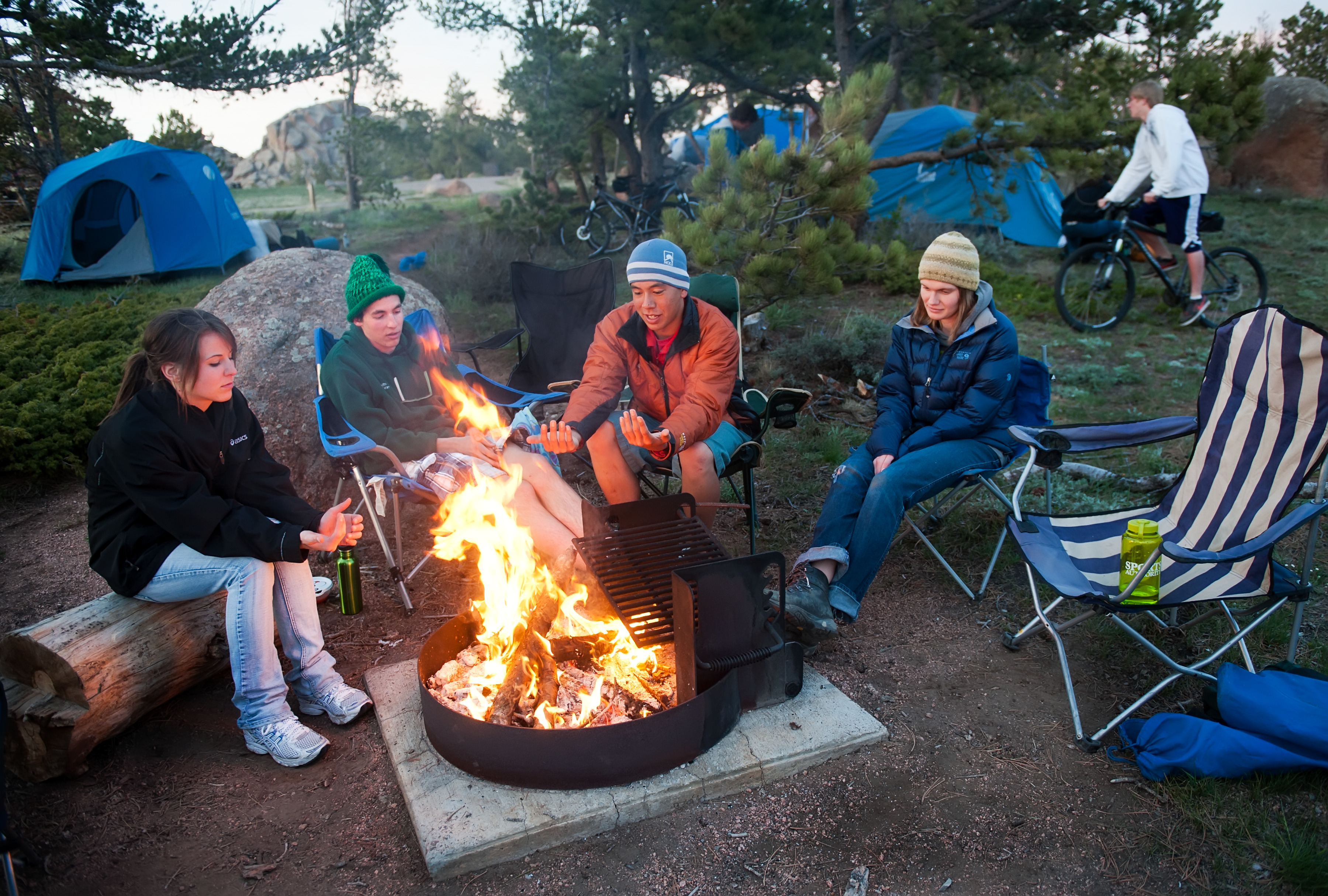 Students sit around a campfire.