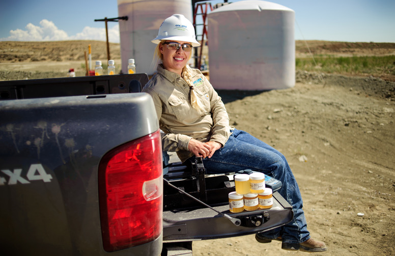 An alumni sitting on the tailgate of truck in the field of the job post grad.
