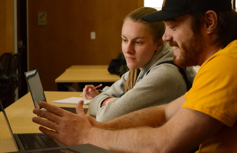 two people look at a laptop screen together