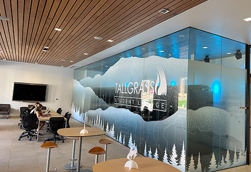 open space with tables and chairs for studying and a glass wall with the Tallgrass logo