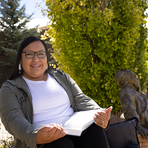 SER Alumna sitting next to statue of Socrates outside the College of Law