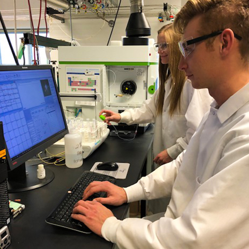 two students in a lab looking at a computer screen