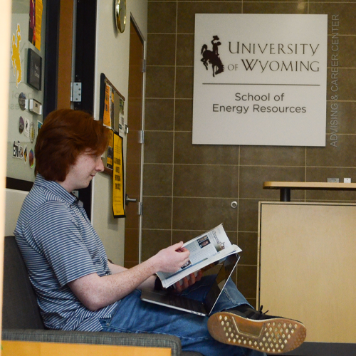 A student waiting in a hallway to meet with an advisor