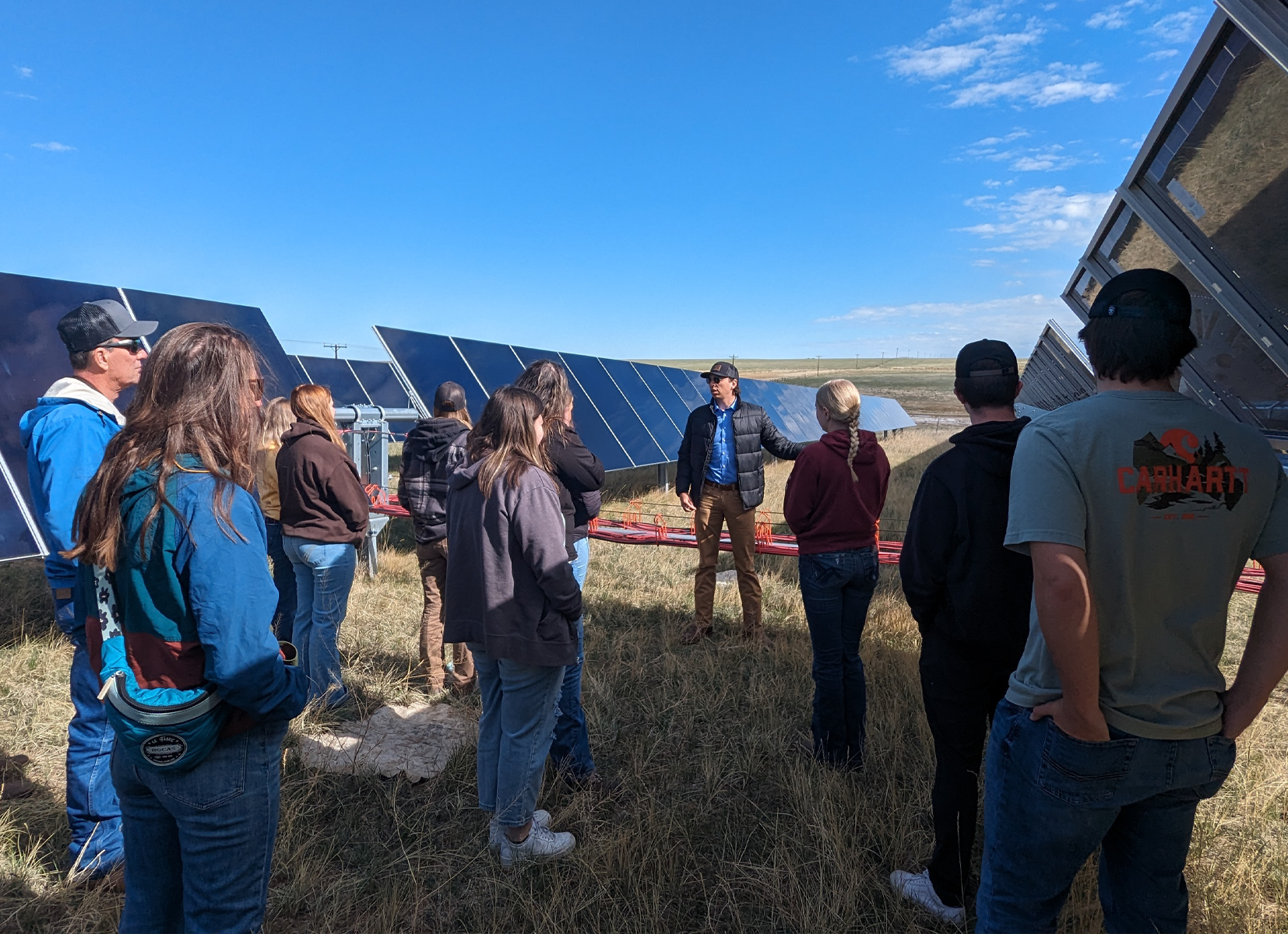 students on a solar farm listening to a UW alumni talk about solar energy