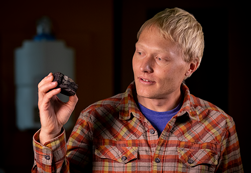 research scientist holding a chunk of coal