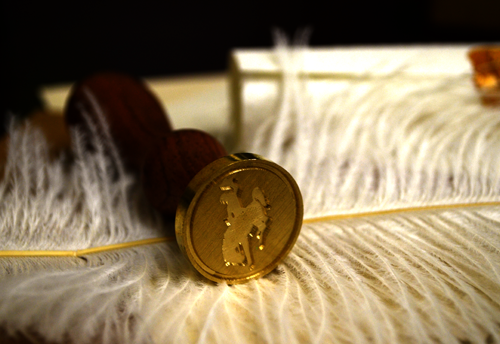 a wax seal press of the cowboy logo on a feather