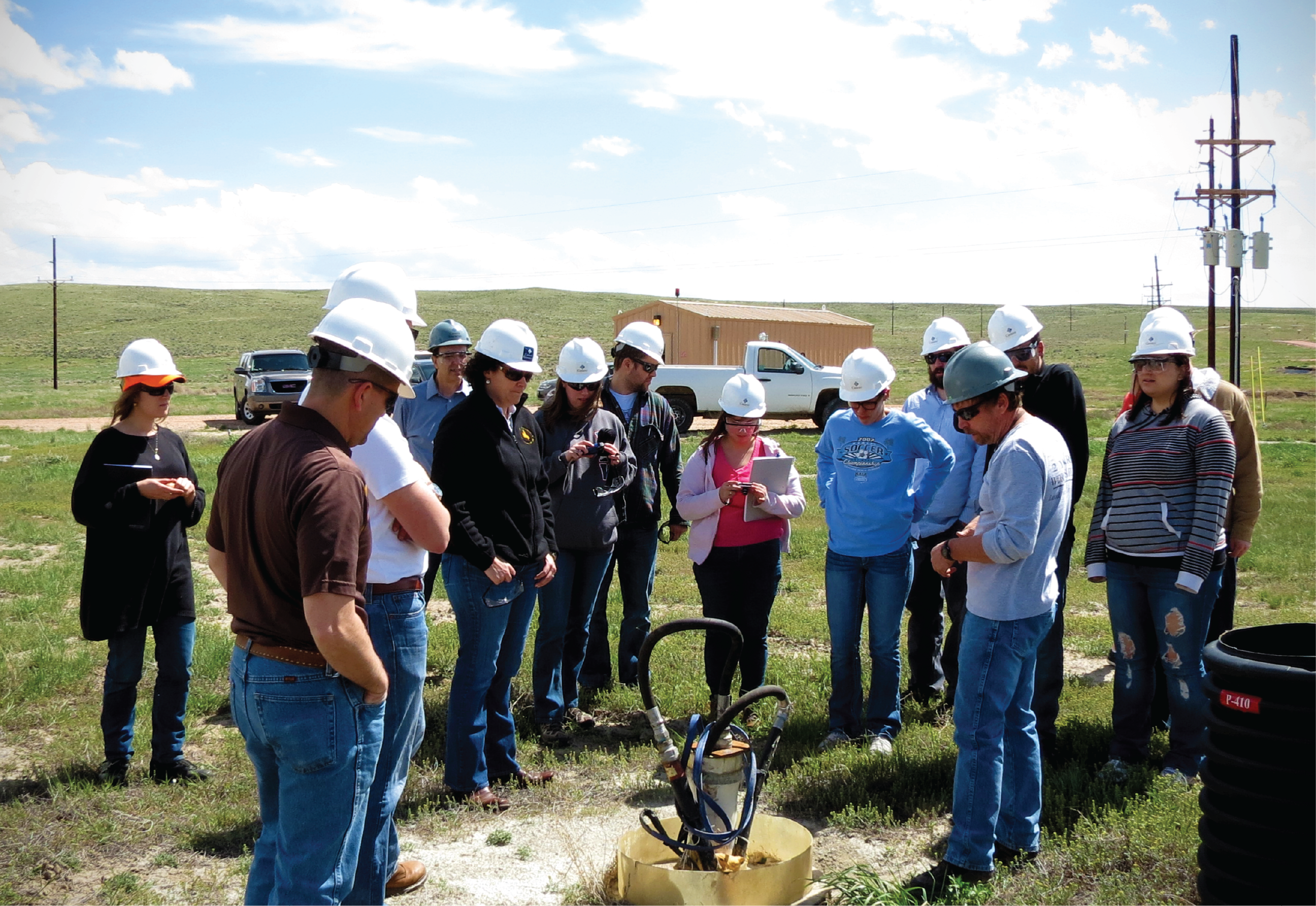 a group of people with hard hats looking at a uranium wellhead