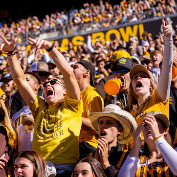 Students cheering at a fall football game.