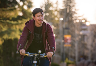 A student rides their bike through Prexys Pasture.