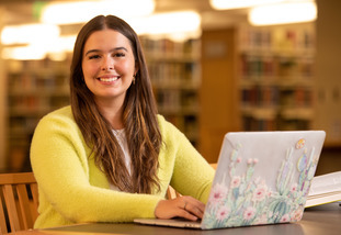 Student studying with laptop in Coe Library.