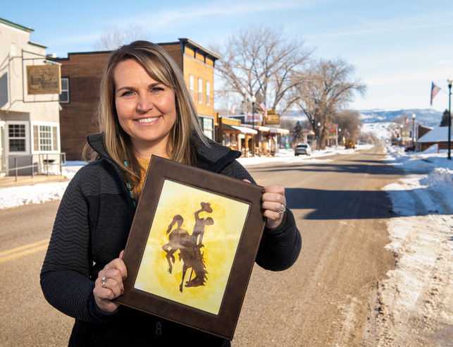 An alumnus of UW holding a bucking horse sign in a small town.