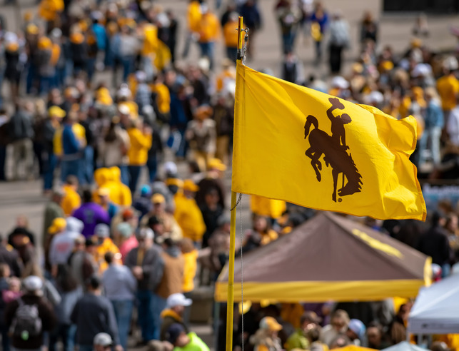 A bucking horse flag flying above the tailgating crowd outside War Memorial Statdium.