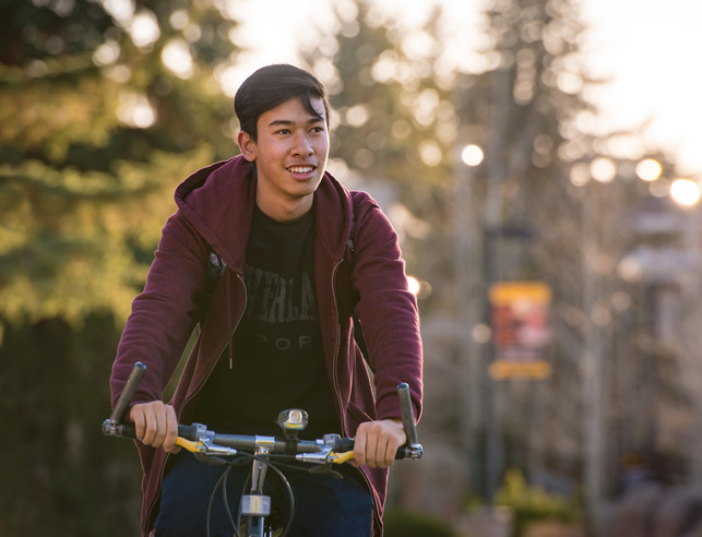 A student rides their bike through Prexys Pasture.