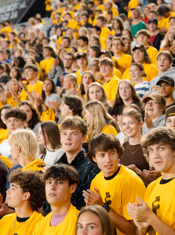 A large crowd of new UW students wearing gold shirts smile at the camera.