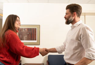 Two people shake hands in an office on UW’s campus.