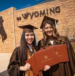 Two students pose at graduation.