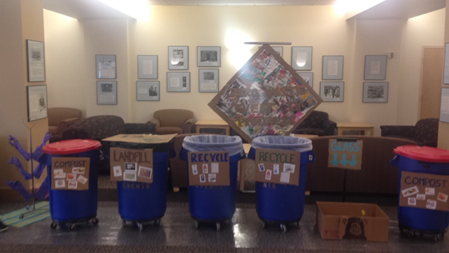 Picture of the zero waste setup at the 2017 Shepard Symposium. 4 trash cans with signs indicating where to put each type of waste.