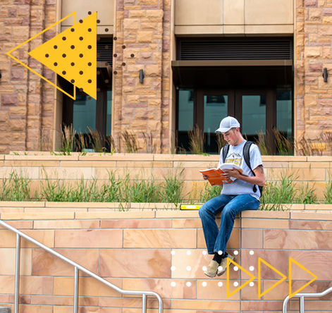 Student sitting on a wall looking at a notebook