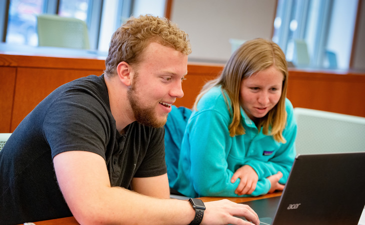 two students working on a laptop