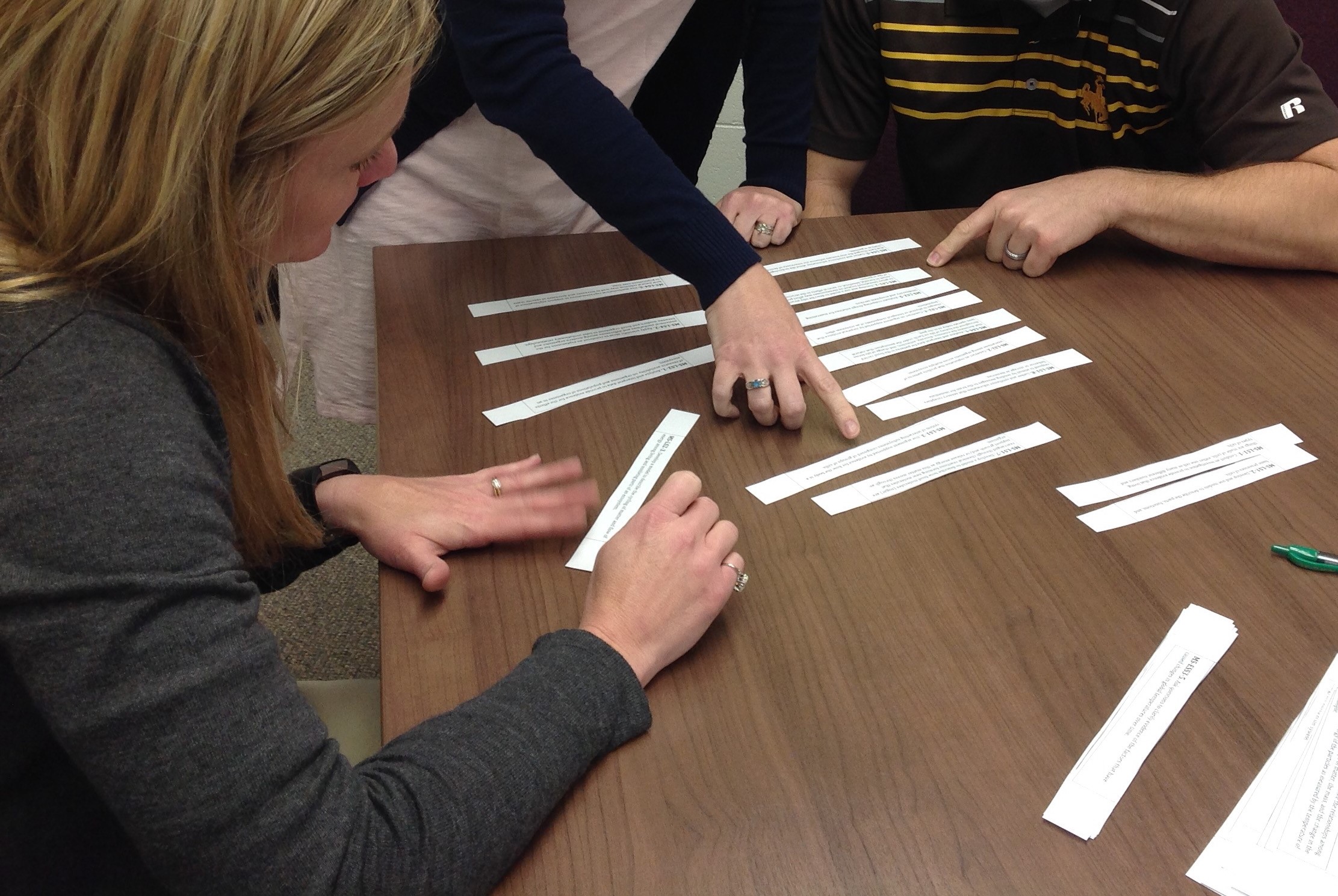 Teacher hands collaboratively ordering strips of paper