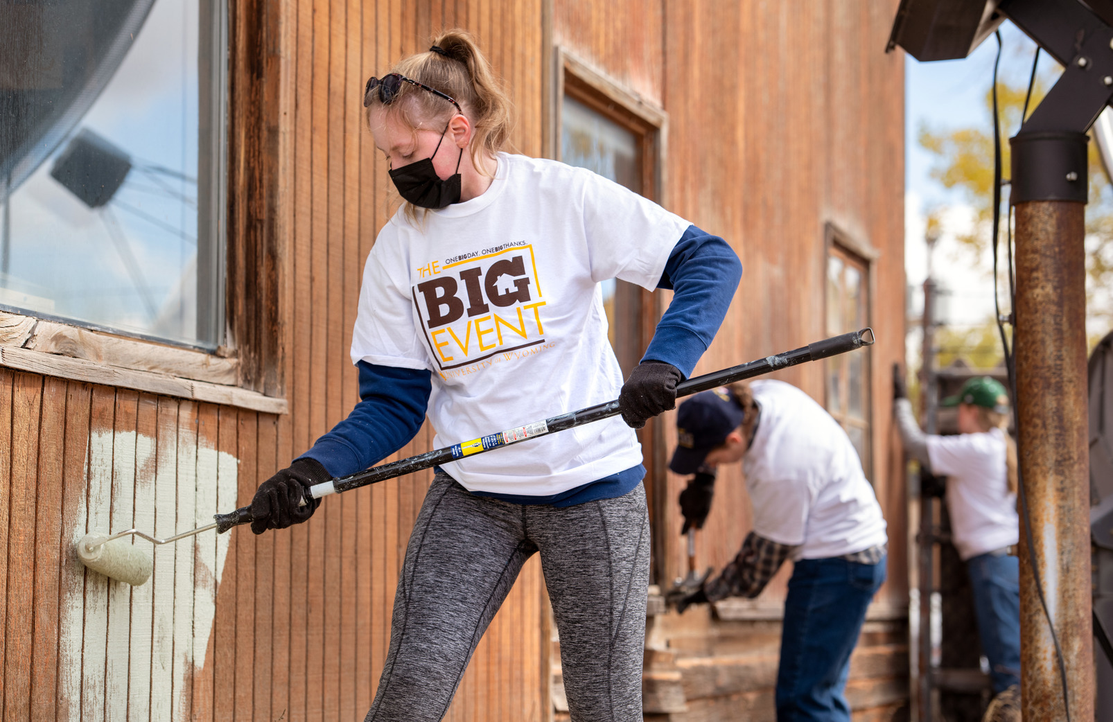 A UW student painting a building outside during The Big Event