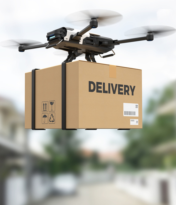 A drone carring a package that says, delivery, on the side of the box.