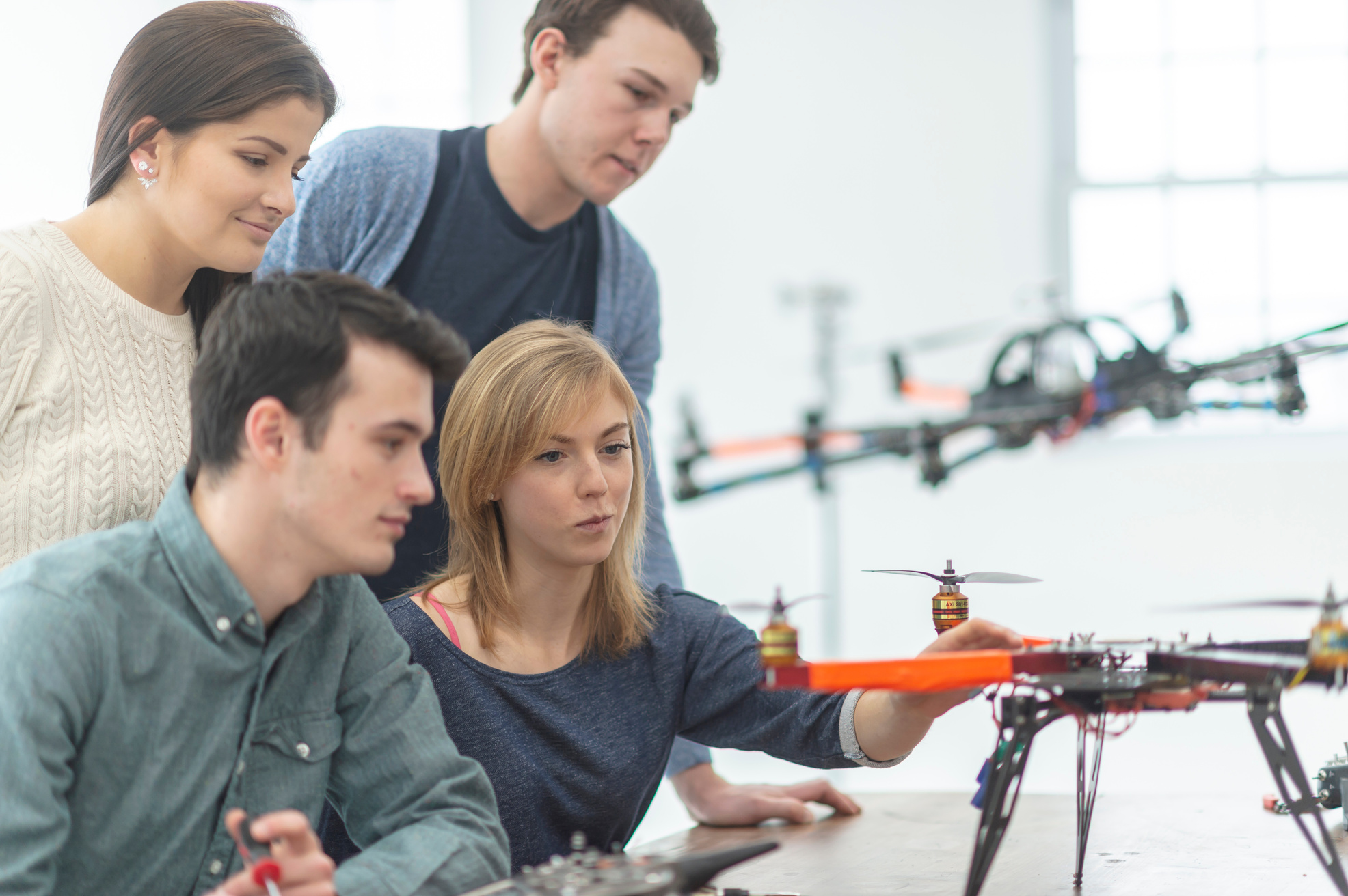 People sitting at tables looking at different drones.