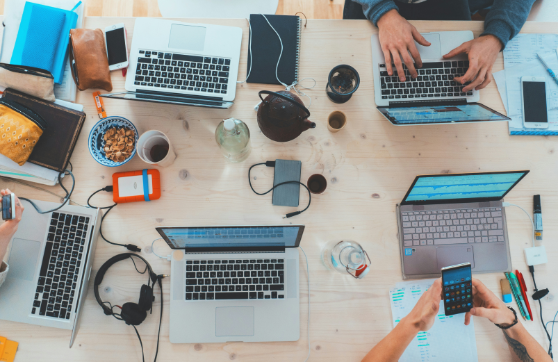 A overhead image of a table with several laptops.