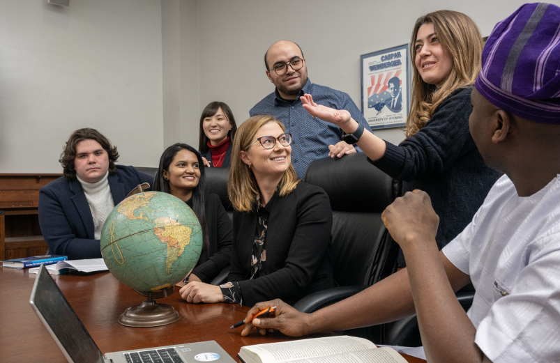 A group of people having a discussion and looking at a globe.
