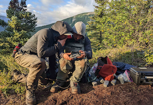 Two students looking at a device that controls a drone.