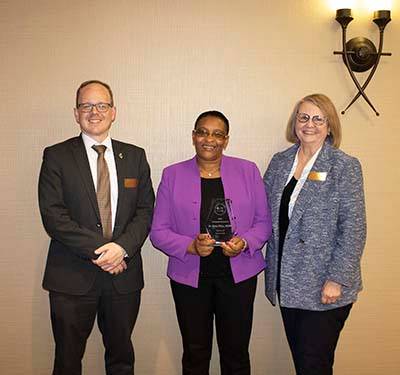 Two women and one man standing for an awards ceremony.