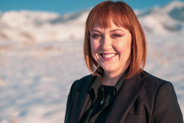 Woman standing outside against a snow covered background.