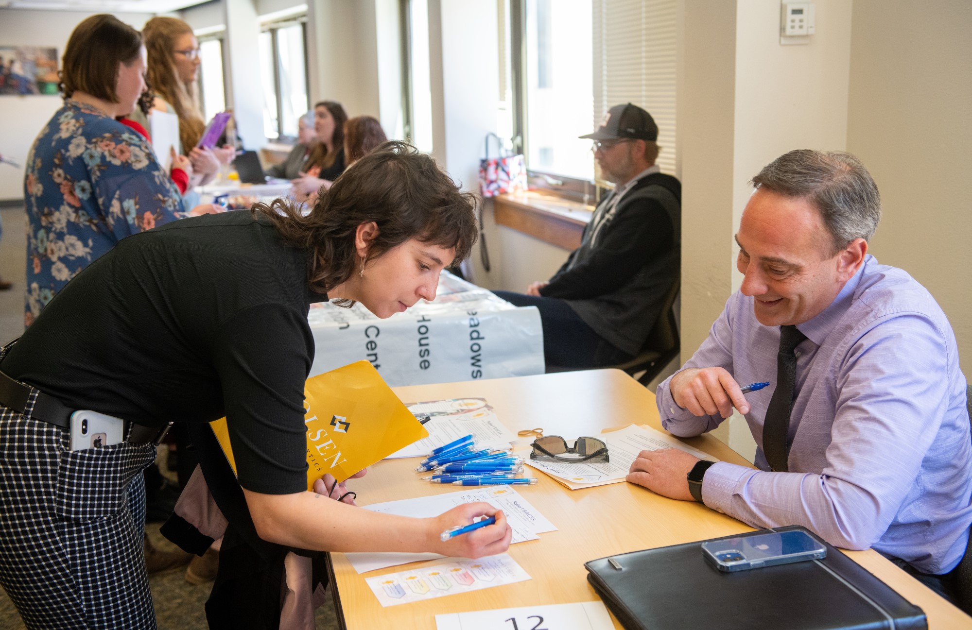 A student leans down to write something on a table.