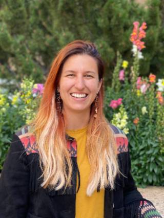 Sabrina White smiling in front of flowers.
