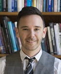 photograph of Dr. Nevin Aiken in front of a bookshelf